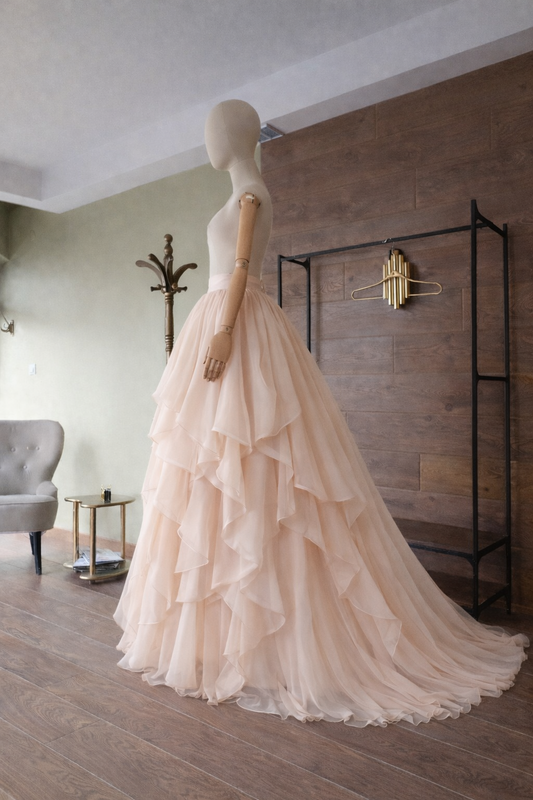 Mannequin wearing a beige ruffled gown in a room with a wooden floor and wall. Designer Asya Kolarova